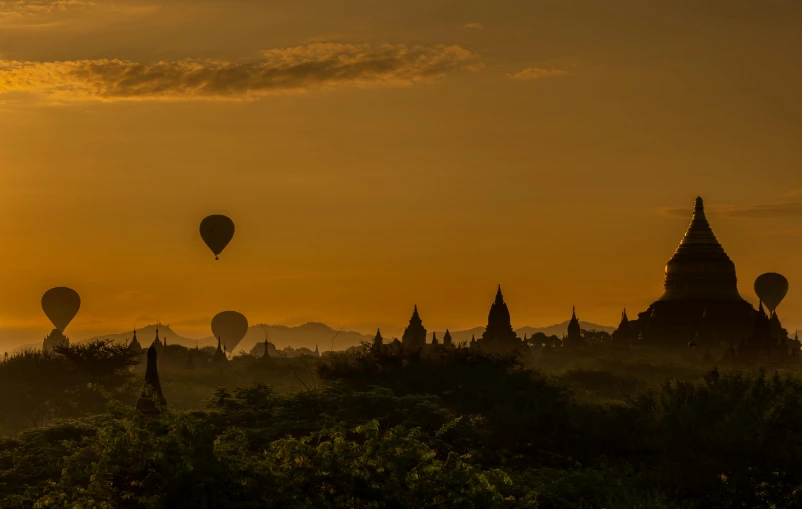 balloons flying high above the land and surrounding a temple