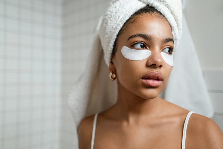 a woman in a towel with a piece of makeup on her face