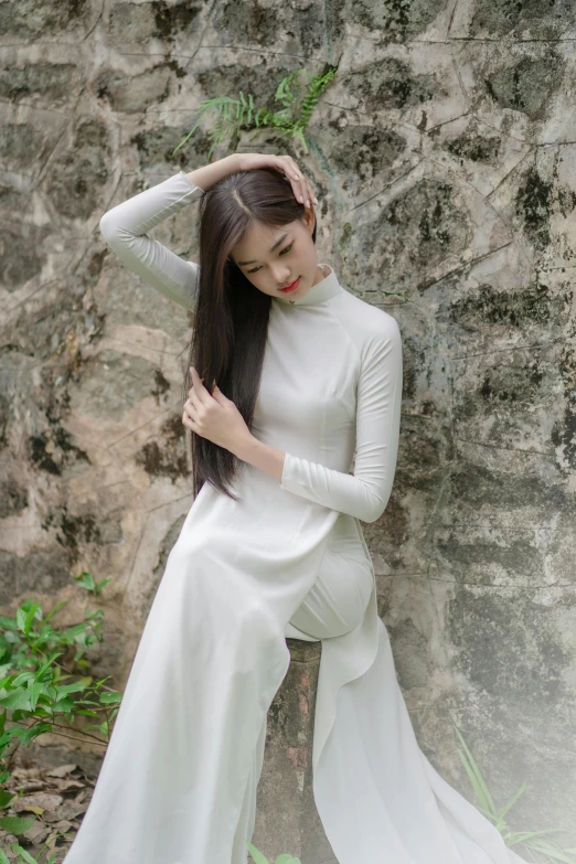 a woman sitting on top of a rock in white