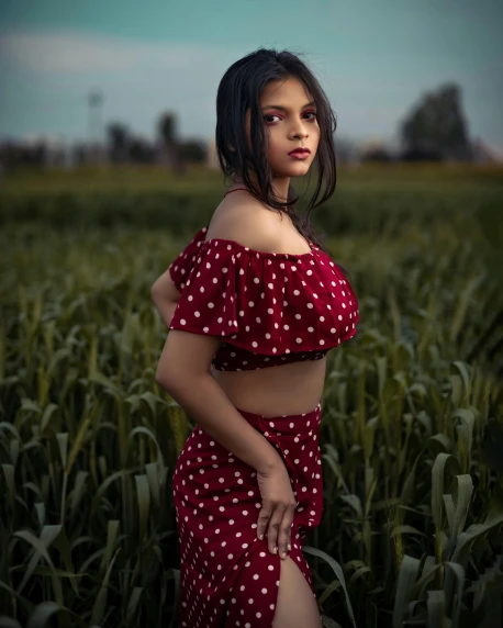 a woman in red polka dotted top standing in a field