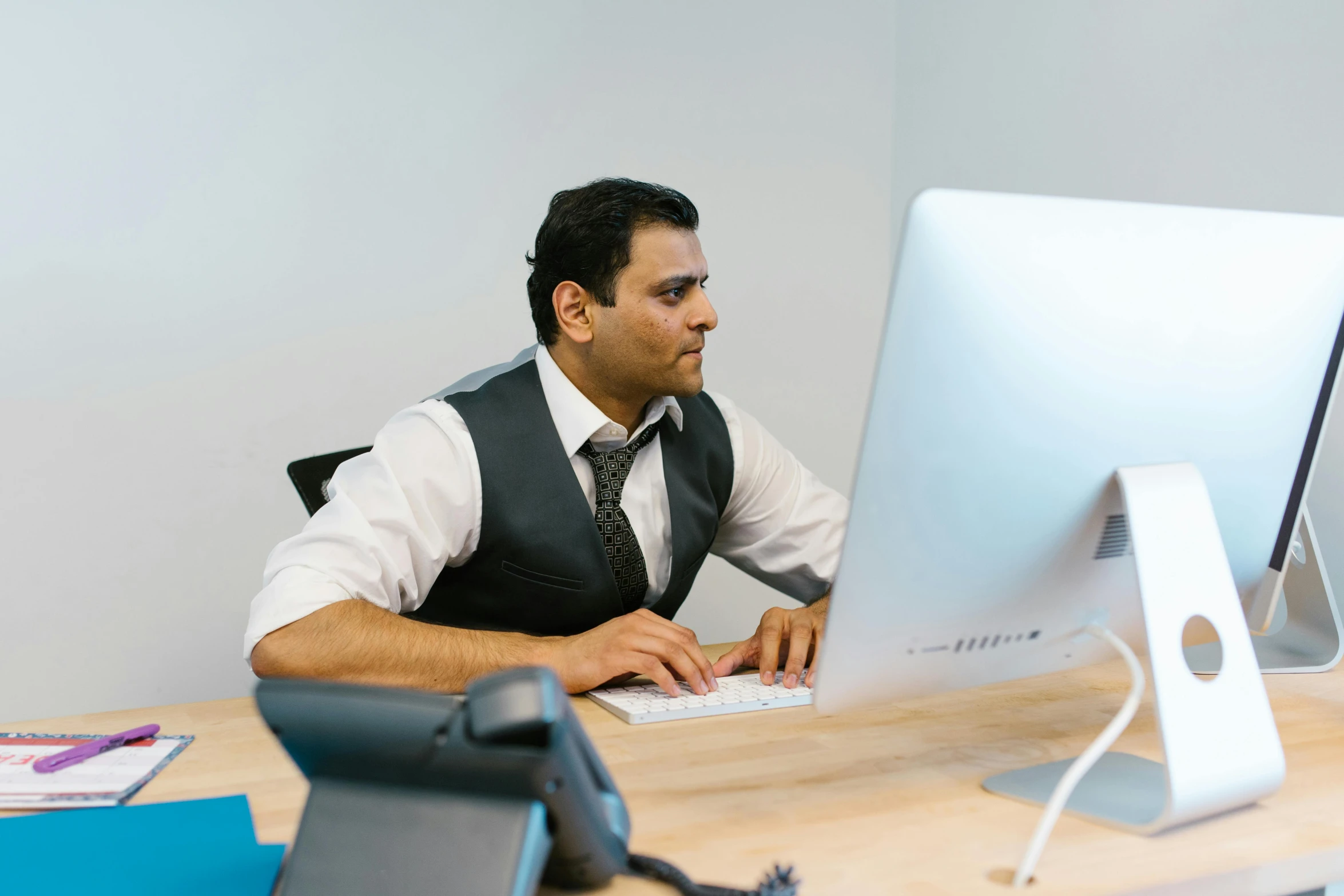 man in suit working on computer at desk