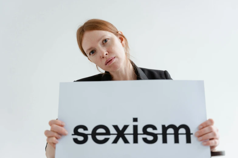 an image of a woman holding a sign with the word sexism