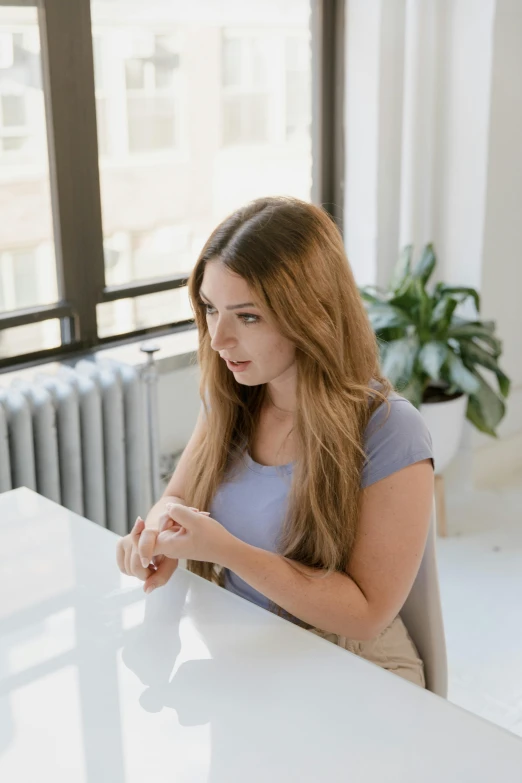 a woman is sitting at a table and looking at her phone