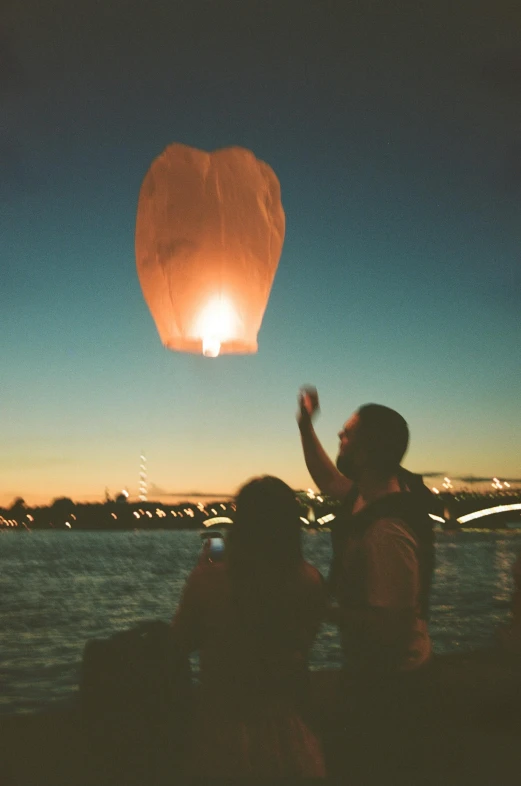 a couple is watching the sky lantern being released