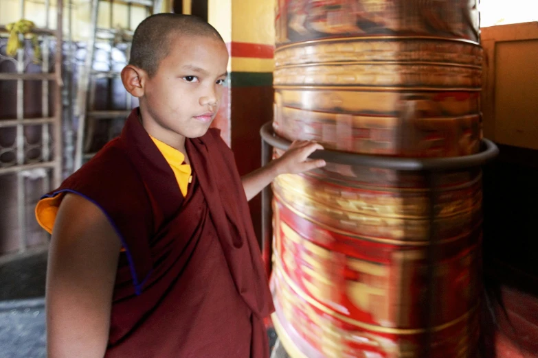 a monk looks on as he holds a tall vase