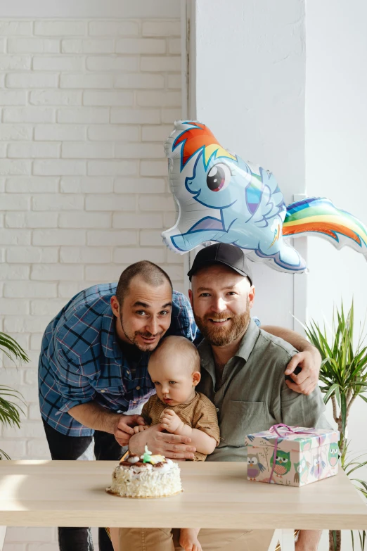 man holding a child and posing next to a cake