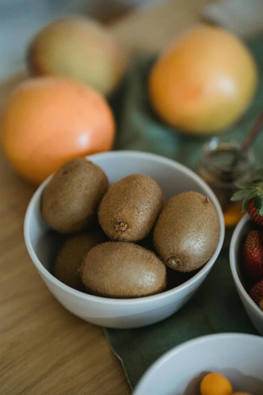 three bowls of fruit on a table with oranges and gs