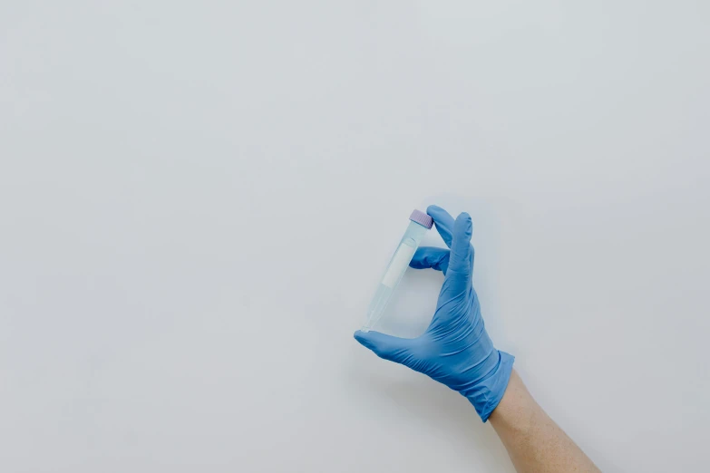 two hands in blue surgical gloves hold a tube
