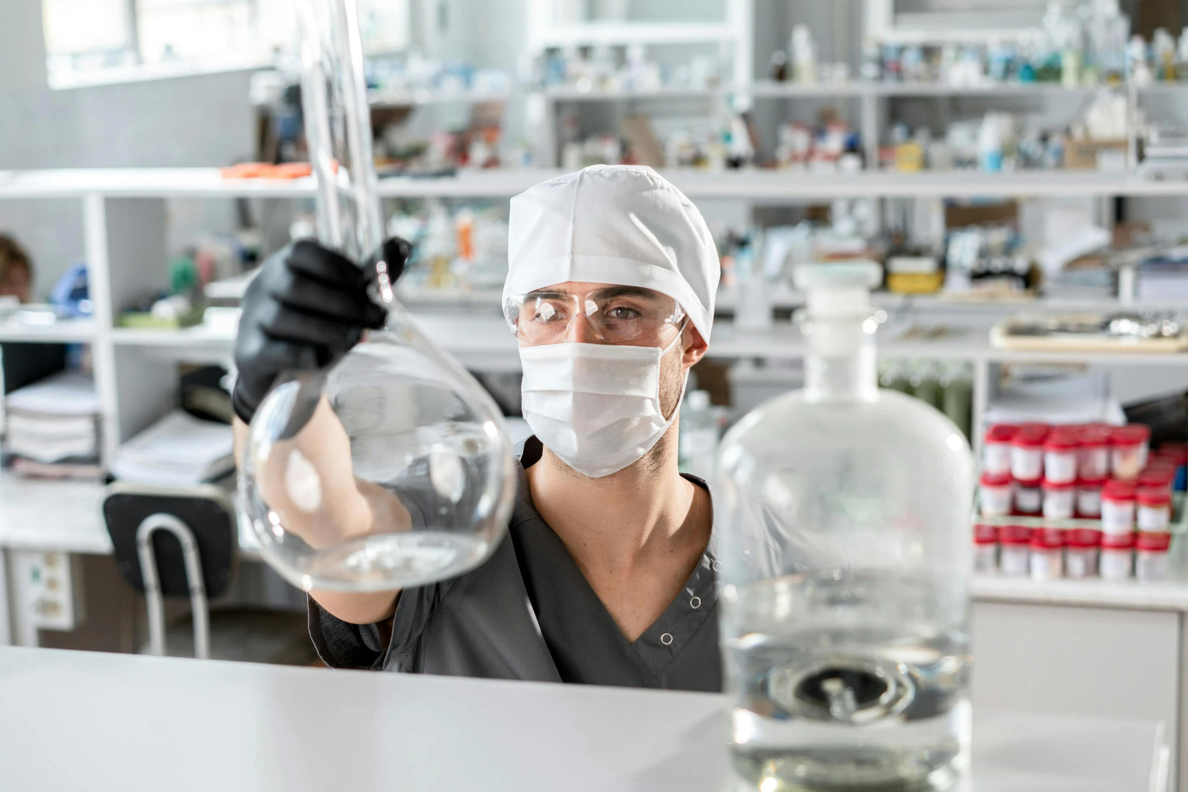 a female wearing a face mask and holding a glass with water in it