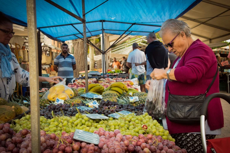 a woman selecting fruit from an outdoor market table