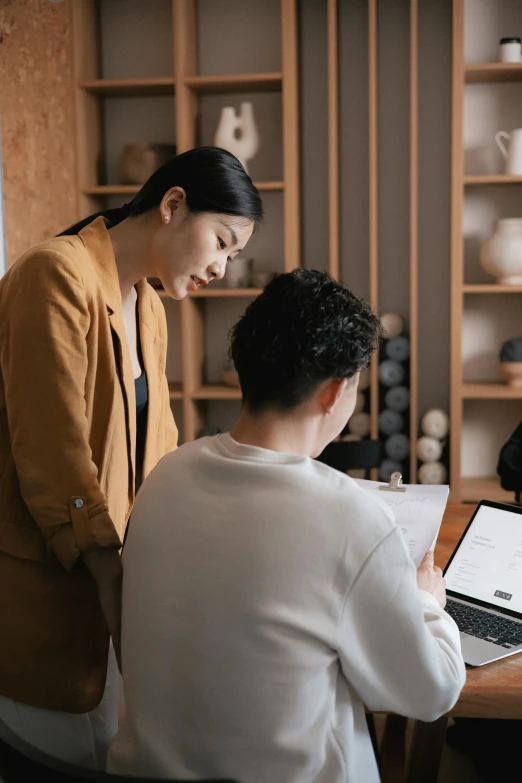 two people are sitting at a desk working on an electronic device