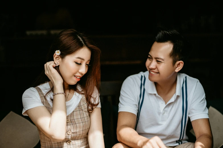 a woman holding a flower is laughing next to a man