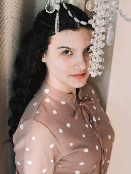 a woman with a brown polka dot dress and a pearled head piece