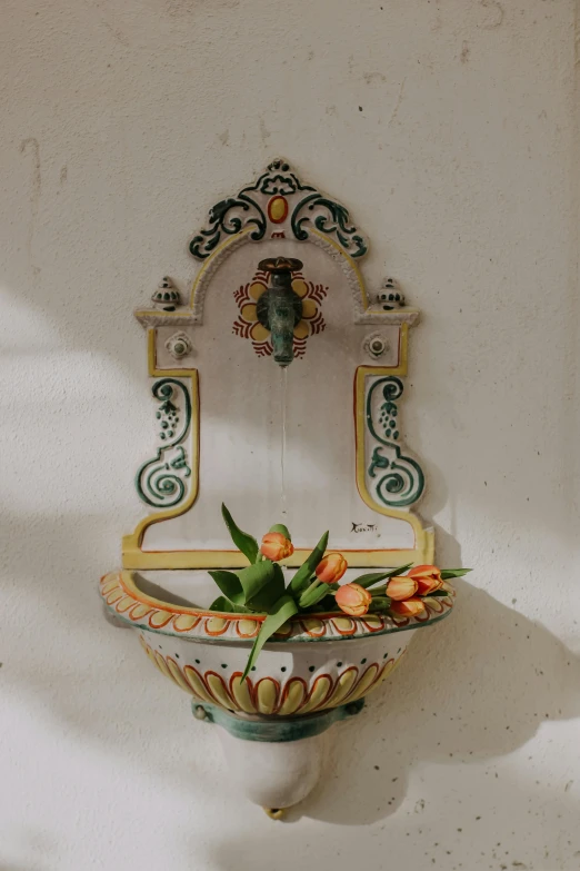 a colorful sink on the wall next to a vase with flowers