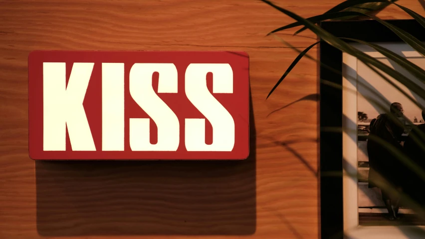 a red sign on a wooden wall reads kiss