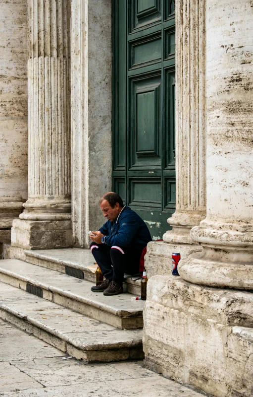 a man sitting on a steps by an entrance and a building