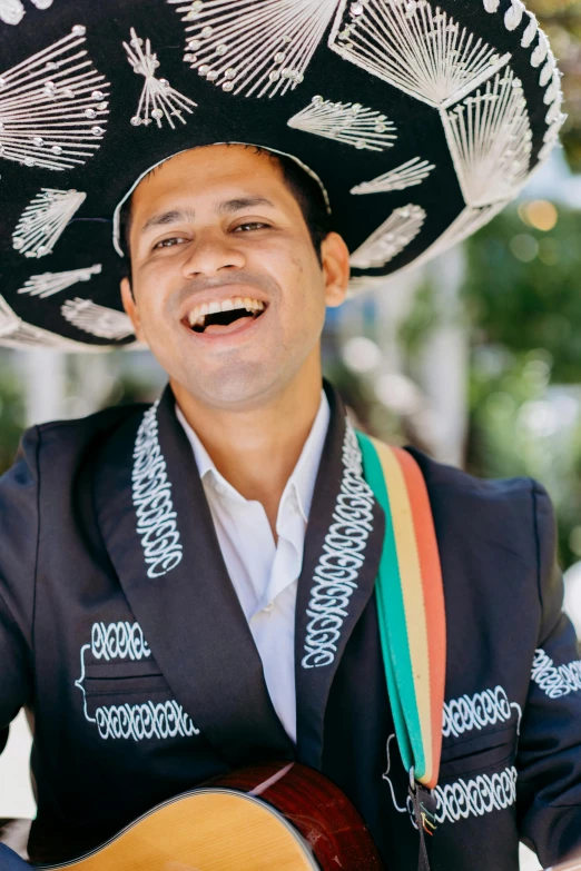 mexican man wearing sombrero playing an acoustic guitar and singing