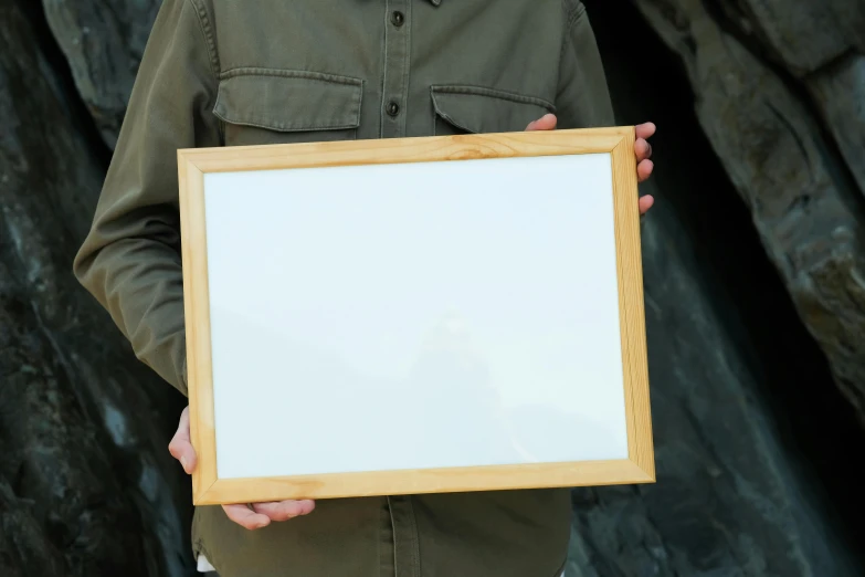 a man holds up an empty wooden picture frame