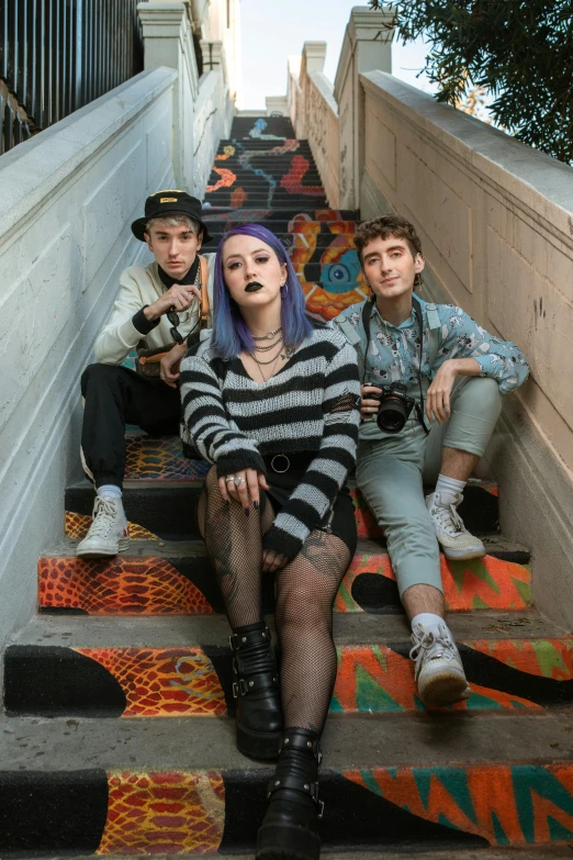 three young men and a woman sitting on a stair way