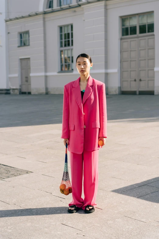 a woman in pink suit standing outside of a large building