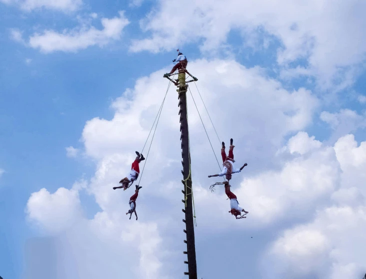 four men hanging from the roof on a high pole