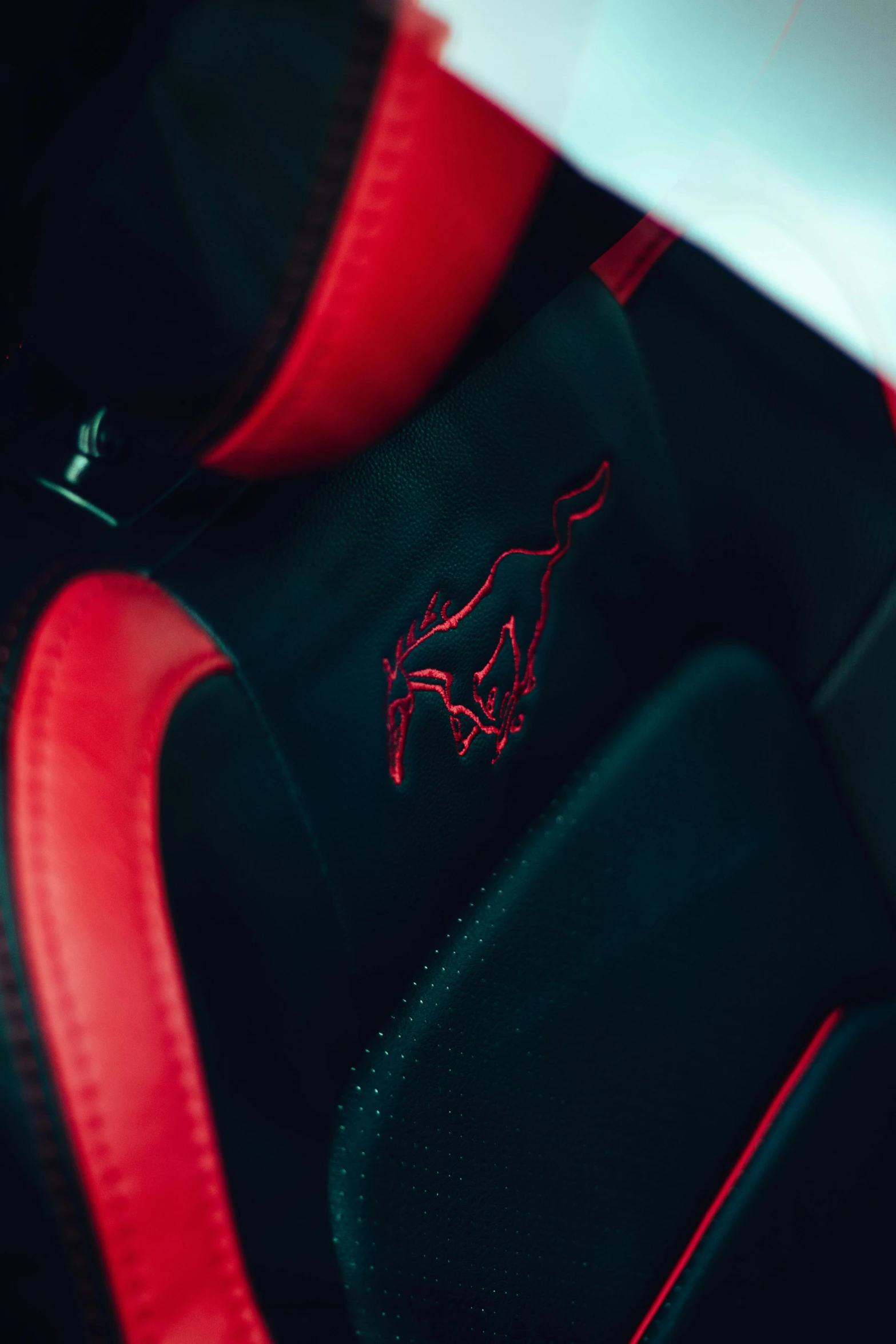 a red mustang emblem on the seat of a car