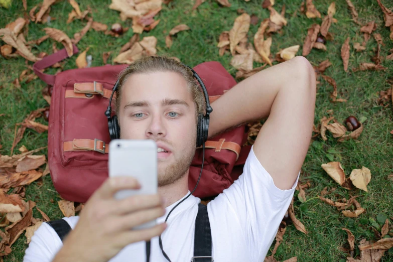 a young man sitting on the grass holding his cell phone to his ear