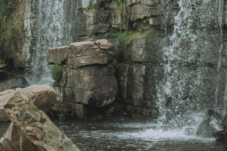 a man swimming in a river near some large waterfall