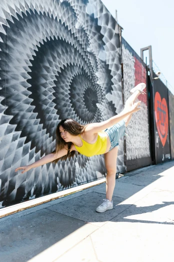 a woman is stretching in front of a wall