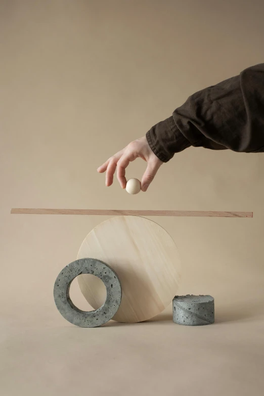 the hand is balancing a ball on a piece of wood