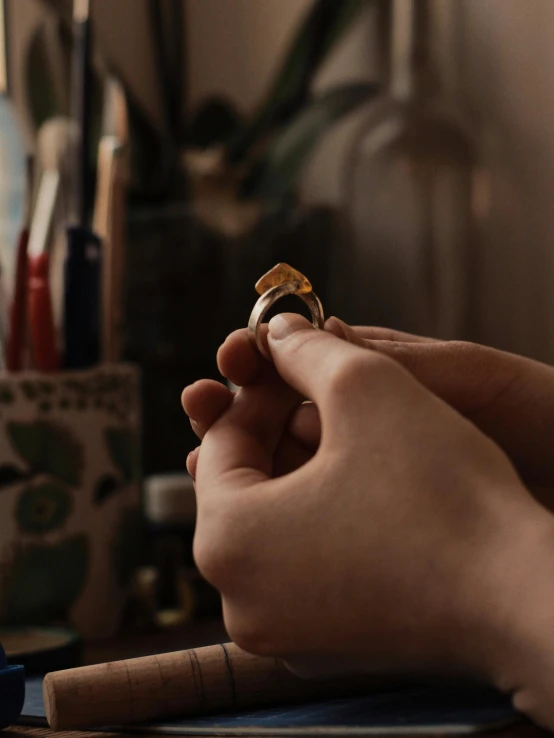 person holding a gold ring on their right hand