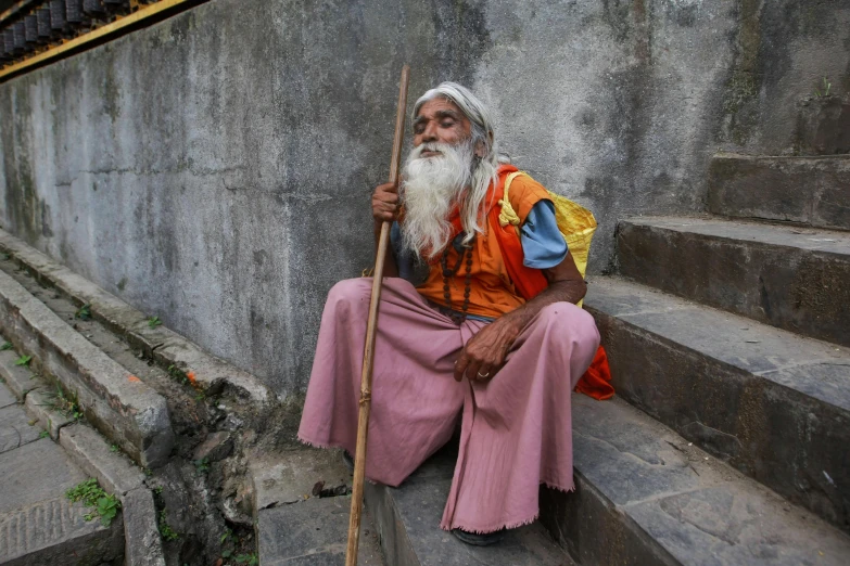 man sitting on steps holding a stick