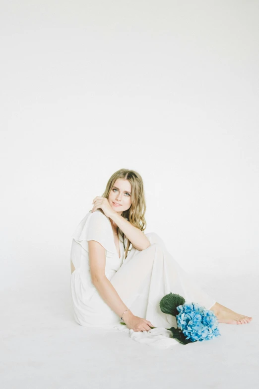 a woman sitting on the floor with a bouquet of flowers