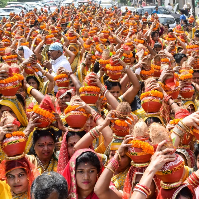 many people wearing orange are standing in front of cars