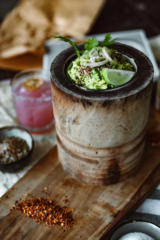 an empty wooden barrel sitting on a table next to some spices and a bowl of food