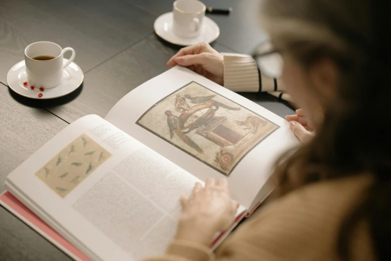 a woman reading a book and drinking tea