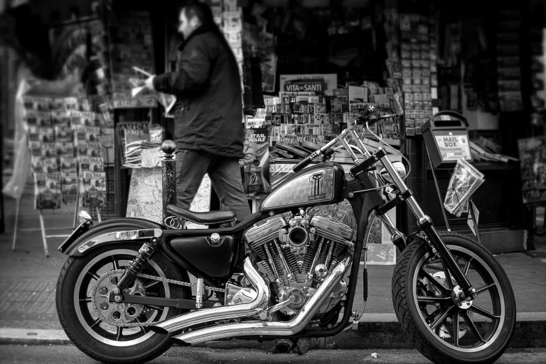 black and white pograph of a man standing next to his motor cycle