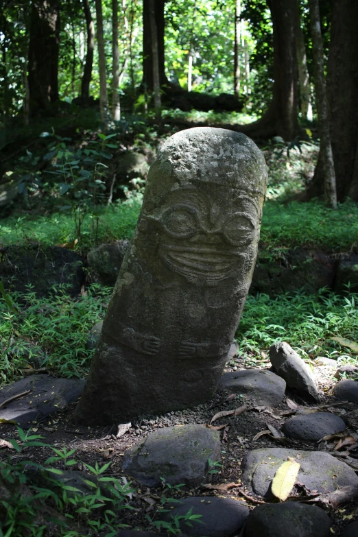 a large stone headstone in a forest setting