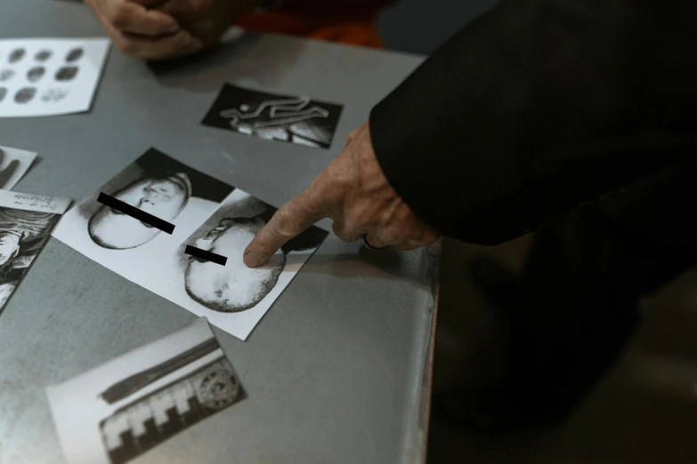 a person pointing at some pictures on the table