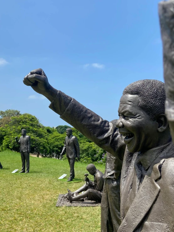 a statue of a man pointing to the sky in front of other statues