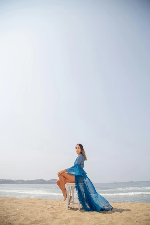 a young lady sits in a chair on the beach