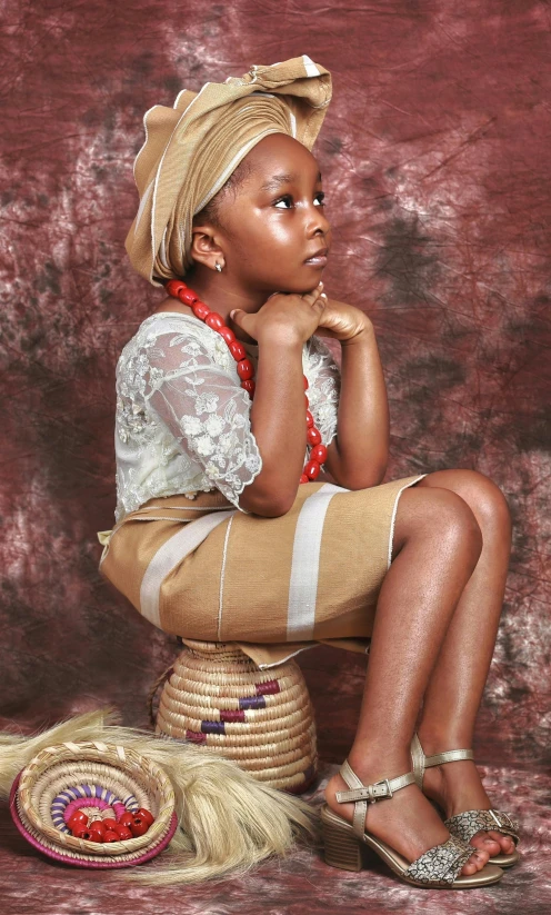 a black woman in traditional african clothing is sitting on a chair