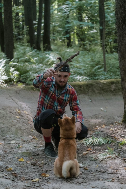 a man kneeling down petting a dog next to a tree