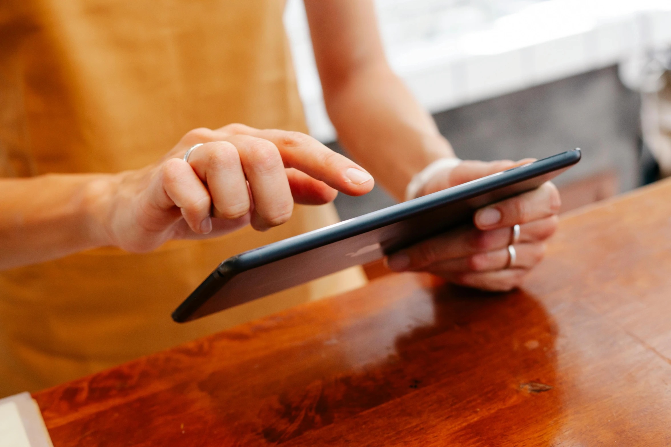 a woman using an electronic device on a wooden table