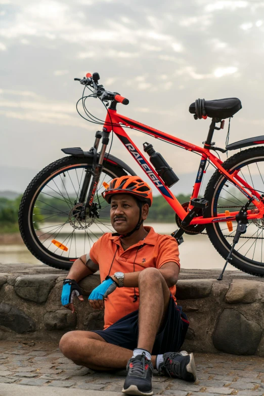 a man sitting next to a bike and some dirt