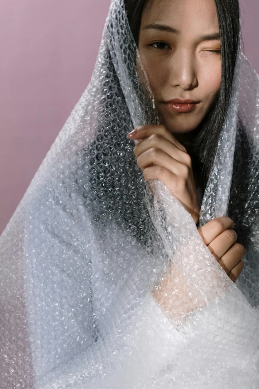 a woman standing in front of a mirror covering her face