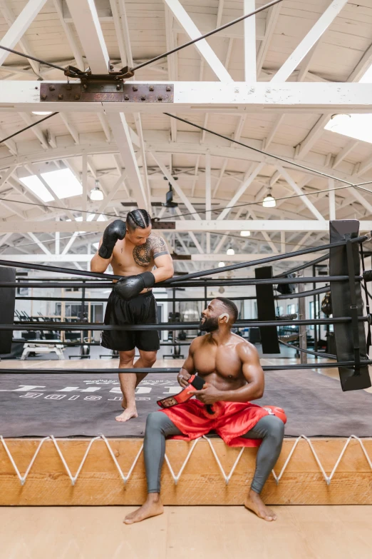 an african american fighter in boxing gear, sits on the edge of a bench