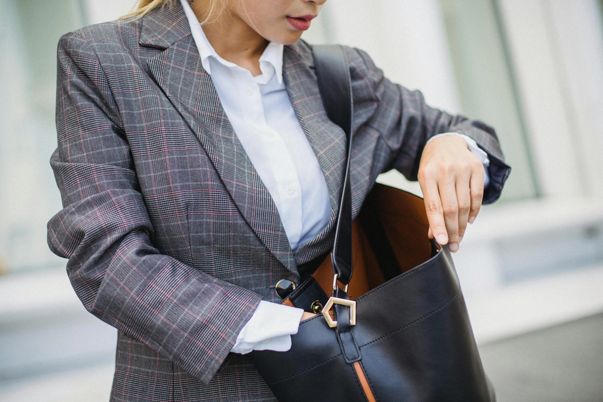 a woman holding a handbag while looking down at her