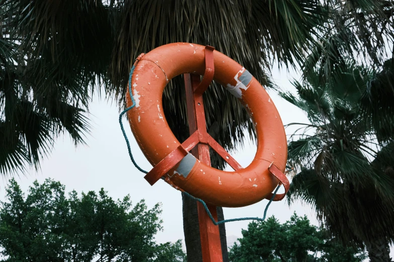 an inflatable orange sign with a red and white stripe next to a palm tree