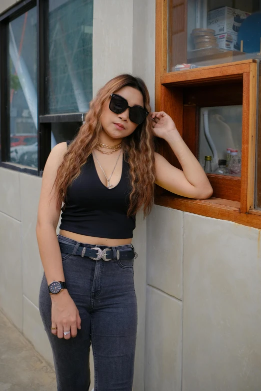 a woman leaning up against a window with sunglasses on